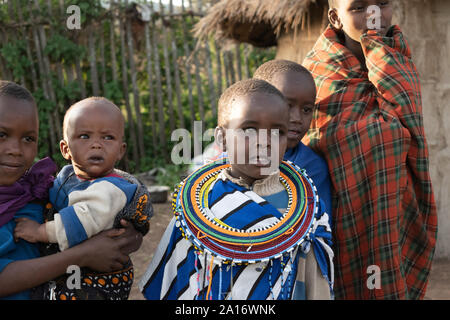 Masai bambini in abito tradizionale sono responsabili per i fratelli più giovani nel villaggio. Foto Stock