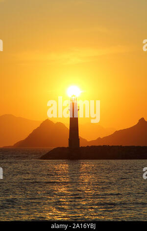 Seascape al tramonto. Faro sulla costa. Città balneare di Turgutreis e tramonti spettacolari Foto Stock