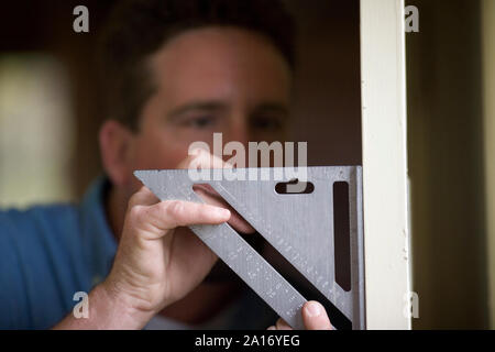Builder maschio la misurazione di una porta. Foto Stock