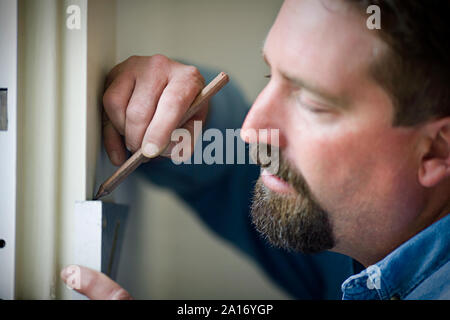 Builder maschio la misurazione di una porta e contrassegnarla con una matita. Foto Stock