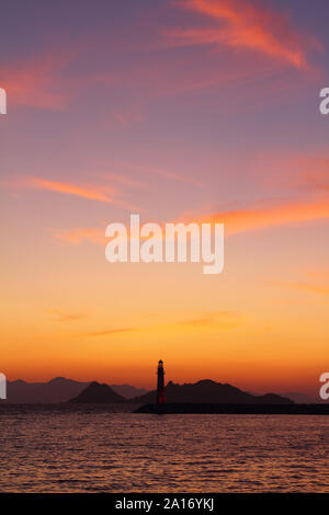 Seascape al tramonto. Faro sulla costa. Città balneare di Turgutreis e tramonti spettacolari Foto Stock