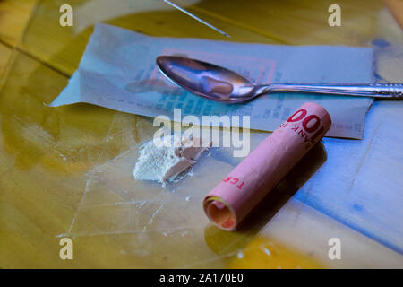 Siringa e Indonesia rupiah e cocaina pronto per usi su un tavolo di legno. La cocaina Tossicodipendenza concetto Foto Stock