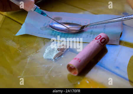 Siringa e Indonesia rupiah e cocaina pronto per usi su un tavolo di legno. La cocaina Tossicodipendenza concetto Foto Stock