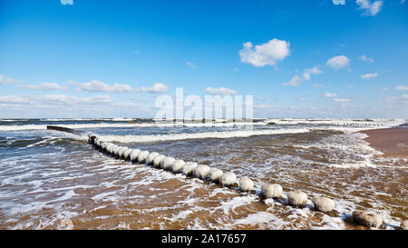Spiaggia con un gelido frangiflutti in legno in una giornata di sole. Foto Stock