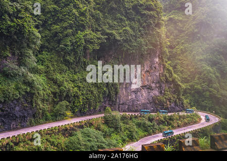 Gli autobus con i turisti guidare su per la strada di avvolgimento di 99 spire alla sommità della montagna Tianmen, Zhangjiajie National Park, Hunan, Cina Foto Stock