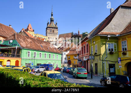 La piazza centrale di pietra in ciottoli street con case colorate all'entrata della cittadella, con la torre di porta in background. Sighisoara, Romania - Luglio Foto Stock