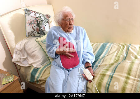 Signora anziana per andare a letto con una coperta elettrica e bottiglie di acqua calda la Gran Bretagna Regno Unito Foto Stock