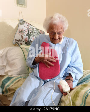 Signora anziana per andare a letto con una coperta elettrica e bottiglie di acqua calda la Gran Bretagna Regno Unito Foto Stock