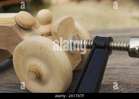 Fatte a mano giocattolo di legno per il ragazzo. Il processo di incollaggio. Bloccata dalla pinza Foto Stock