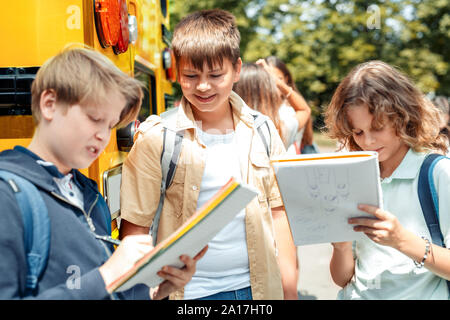 Compagni di classe andando a scuola in autobus ragazzi close-up assegnazione facendo in notebook sorridendo felice Foto Stock
