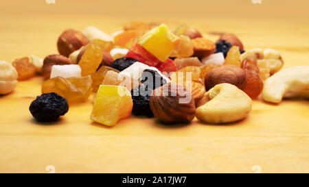 Tutti frutti. Mix di frutta secca (uva passa, cedro, mango) e dadi (mandorle, nocciole) sulla luce di legno superficie lucidata Foto Stock