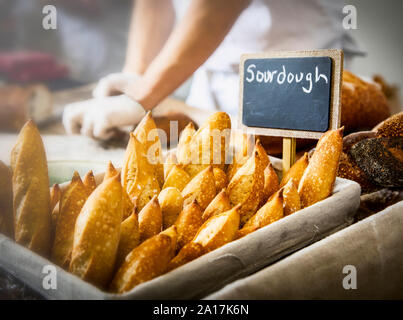 Baguette di pane di pasta acida con chef lavorando in background Foto Stock