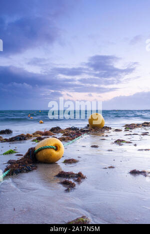 Indicatore giallo boe posa sulla spiaggia durante la bassa marea, Plage de Kervillen, Francia Foto Stock