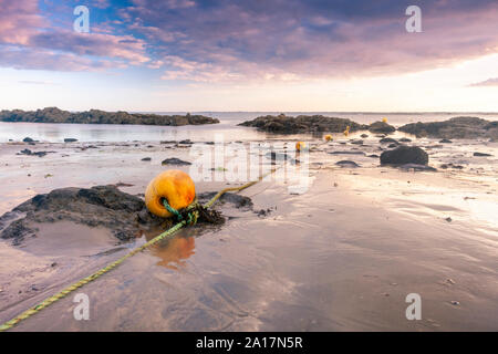 Indicatore giallo boe posa sulla spiaggia durante la bassa marea, Plage de Kervillen, Francia Foto Stock