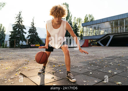 Gli uomini con curva hair giocare a basket all'aperto Foto Stock