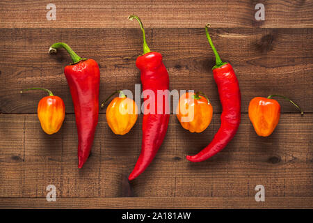 Assortimento di peperoni freschi su una trama di legno scuro dello sfondo Foto Stock