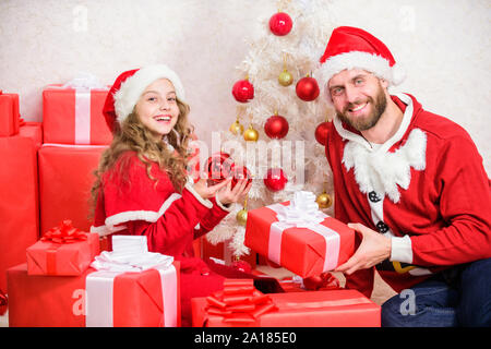 Papà in santa costume dare il dono alla figlia carino kid. Infanzia felice. Natale vacanze in famiglia. Regalo di natale per i bambini. Rendere la vostra vacanza con bambini extra speciale di quest'anno. Babbo Natale concetto. Foto Stock