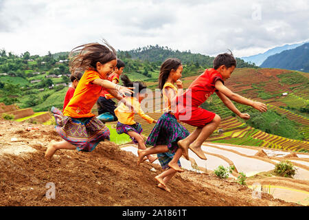 Hmong bambini divertirsi nel fango di montagna in um Cang area Chai, Yen Bai provincia, nella parte nord-occidentale del Vietnam. Foto Stock