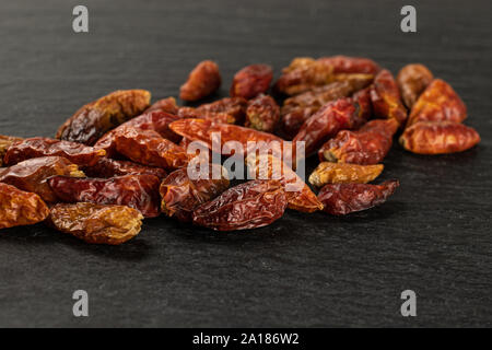 Molto secco intero peperoncino rosso peperoncino sulla pietra grigia Foto Stock