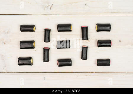 Sacco di tutto il dolce di liquirizia nera candy flatlay su legno bianco Foto Stock
