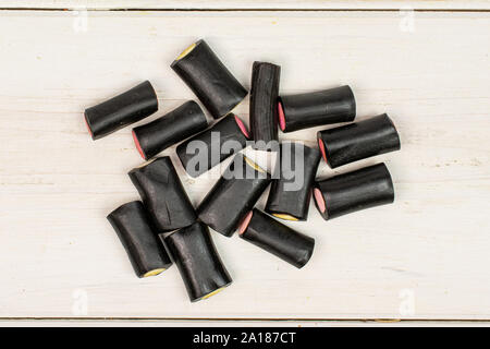 Sacco di tutto il dolce di liquirizia nera candy flatlay su legno bianco Foto Stock