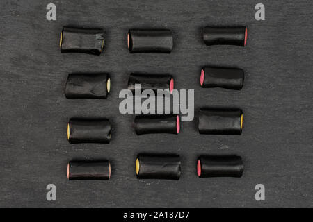 Sacco di tutto il dolce di liquirizia nera candy flatlay sulla pietra grigia Foto Stock