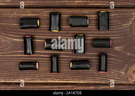 Sacco di tutto il dolce di liquirizia nera candy flatlay su legno marrone Foto Stock
