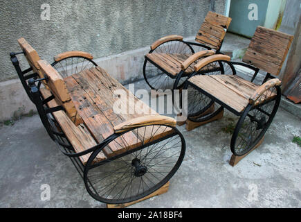 Una combinazione di antiche in legno e sedie in ferro realizzato da beni usati Foto Stock