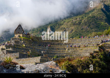 Le antiche rovine della città di Machu Picchu sorgono del sole, la Valle Sacra degli Incas, Perù. I turisti scendono dalle terrazze della città, le rovine di Machu Pichu, la mattina presto. Foto Stock