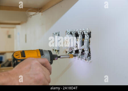 Il lavoro di installare prese elettriche con fili elettrici e connettore installato nel muro a secco di pannelli in gesso cartonato Foto Stock