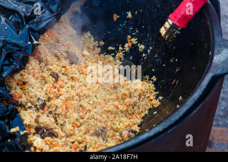 Tradizionale plov uzbeko agnello e riso pilaf cucina outdoor a Kazan. Foto Stock