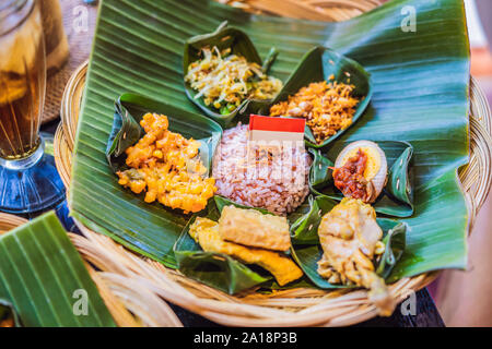 Nasi lemak, Nasi campur, Indonesiana riso Balinesi con delle crocchette di patate, sate DISPOSITIVO HIRON JARAC JUPITER BASSA LILIT, tofu fritto, piccante uova sode, e arachide Foto Stock