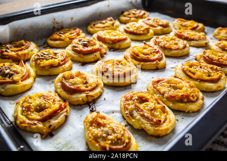 Rotoli di pasta sfoglia con prosciutto formaggio pancetta sesamo sul vassoio da forno Foto Stock