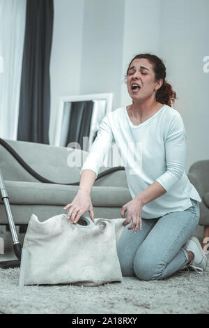 Giovane moglie starnuti mentre la sua pulizia aspirapolvere a casa Foto Stock