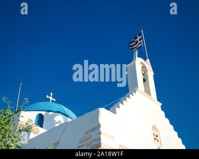 Bianco antico edificio religioso con archi e cupola blu con croce sulla strada di ciottoli in Parikia Paros Grecia sotto il cielo blu Foto Stock