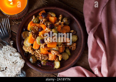 Insalata di festa con arrosti di cavolini di Bruxelles, la zucca, le noci pecan e mirtilli rossi vetrate con miele e salsa di cannella. Foto Stock