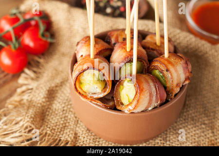 Pancetta avvolto Il cavoletto di Bruxelles è servita con pomodorini in vaso in ceramica. Antipasto rotoli Foto Stock