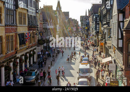 Iconico Eastgate Street a Chester con il tradizionale stile Tudor House e le persone aventi una passeggiata. I raggi del sole creano un atmosfera speciale. Foto Stock