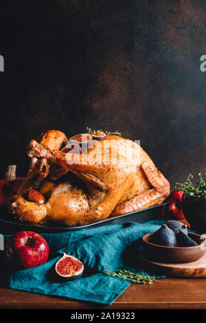 Arrosto di tacchino intero su un tavolo con Apple, la zucca e le figure per la famiglia per la Festa del Ringraziamento. Foto Stock