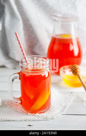 Limonata alle fragole con miele a mason jar e nella caraffa del bianco sul tavolo di legno Foto Stock