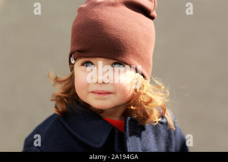 Ritratto di un simpatico elegante un anno bambina indossa un dark blue coat e marrone cappello Foto Stock