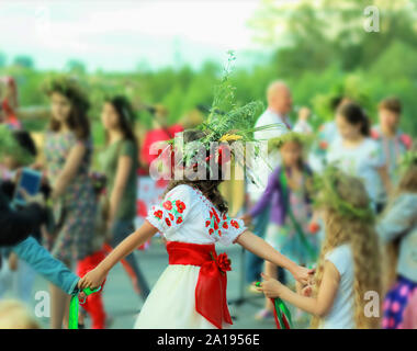 Giovane ragazza che indossa una corona e ucraino etnici abiti ricamati con fiori di colore rosso dancing in un anello per celebrare feste pagane di Ivan Kupala Foto Stock