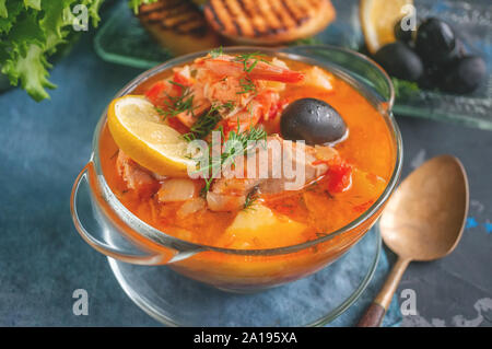 Zuppa di pesce, salmone e merluzzo con patate. Servito con limone e olive. Close up. Foto Stock