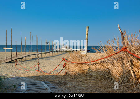 Foodpath circondato da erba alta e barriera con la corda rossa che conduce alla spiaggia e mare sul mare del nord Isola di Texel in Olanda Foto Stock