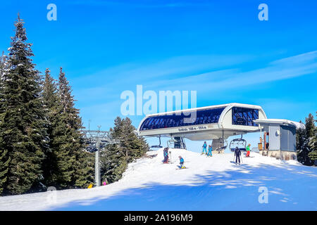 Bansko, Bulgaria - 20 dicembre 2018: Ski resort con vista sulle piste da sci, persone sciare giù da Kolarski a 6 posti ski seggiovia Foto Stock