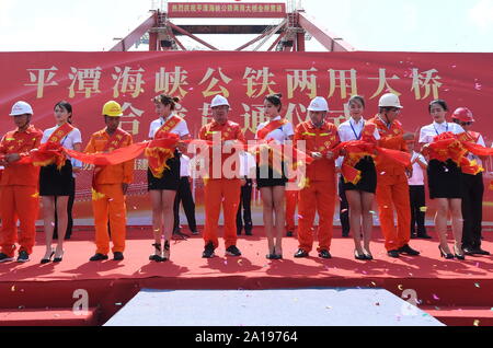 (190925) -- FUZHOU, Sett. 25, 2019 (Xinhua) -- la gente ha tagliato il nastro nel corso di una cerimonia che segna il completamento della struttura principale del Pingtan stretto Road-ponte ferroviario nel sud-est della Cina di provincia del Fujian, Sett. 25, 2019. Cina mercoledì completato la struttura principale della più lunga del mondo cross-sea road-ponte ferroviario nel Fujian. L'ultima trave di acciaio, del peso di 473 tonnellate, è stato avvitato sullo stretto di Pingtan Road-rail Bridge, un altro mega progetto in Cina, mercoledì mattina. Con una sconcertante span di 16.34 km, il ponte collega Pingtan Isola e quattro isolette vicine alla terraferma o Foto Stock