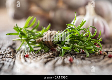 Di rosmarino fresco e spicchi di aglio con spezie sul vecchio tavolo in legno Foto Stock