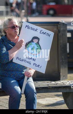 Una donna matura tenendo un cartello e che partecipano alla estinzione della ribellione clima sciopero in Truro City in Cornovaglia. Foto Stock
