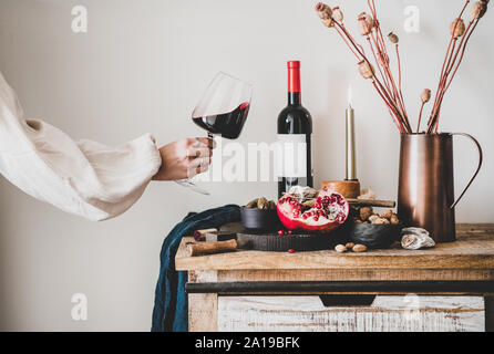 Womans mano che tiene un bicchiere di vino e una serie di spuntini Foto Stock