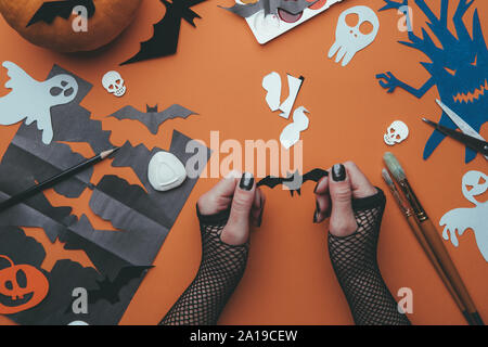 Immagine di sfondi di halloween con la carta i fantasmi, zucca, teschi, mani umane, sfondo arancione Foto Stock